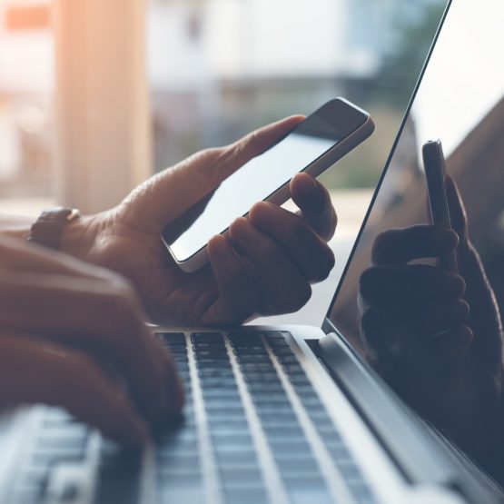 man-working-on-phone-in-front-of-laptop